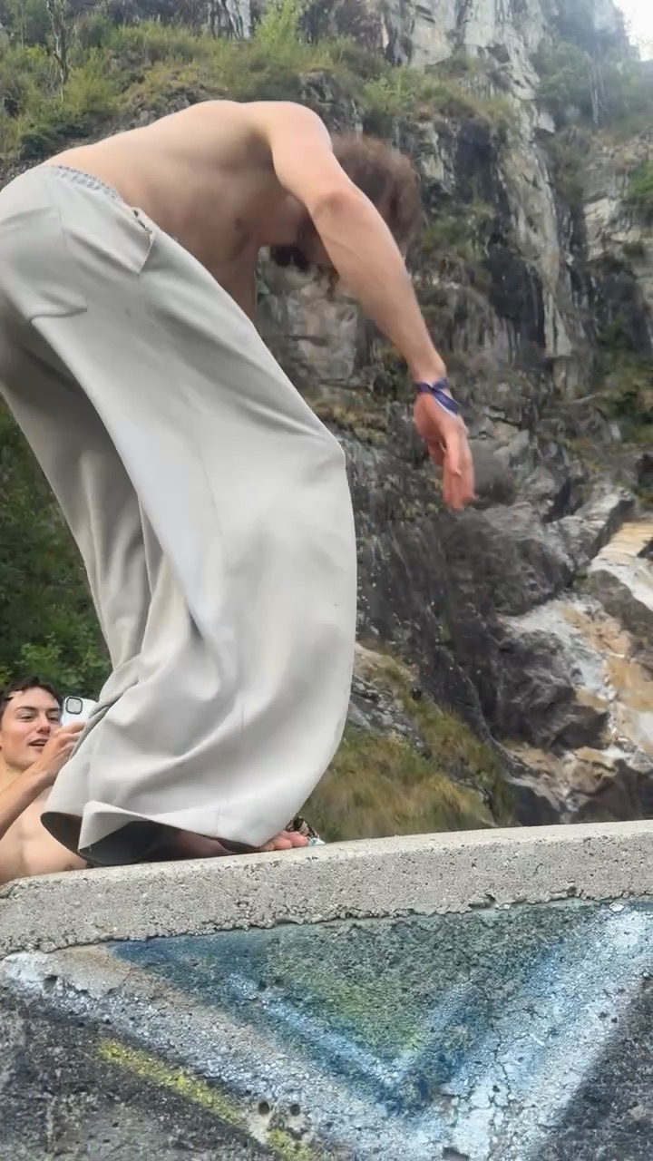 Einer steht barfuss und gebeugt auf der Mauerkante, eine Sekunde vor dem Absprung, unten wartet die Felswand.
