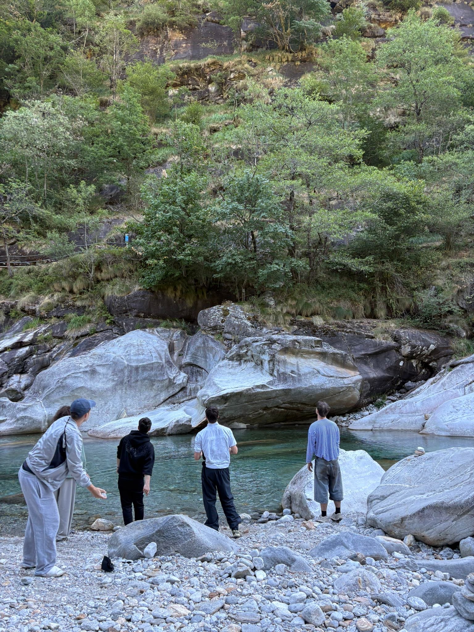 Vier von hinten am türkisen Fluss zwischen hellen Granitblöcken, kurz vor dem Reingehen.